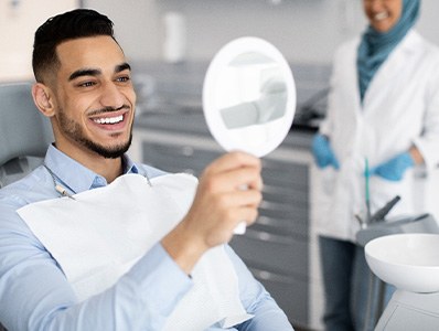 Patient smiling at reflection in handheld mirror