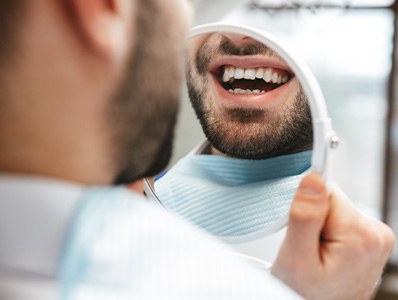 Patient smiling at reflection in handheld mirror