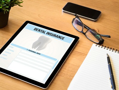 Dental insurance form on tablet next to office supplies