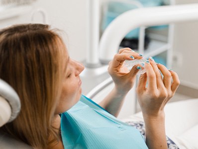 Patient holding clear aligner in treatment chair