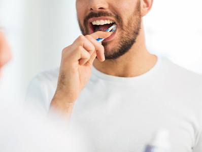 Man in white shirt brushing his teeth