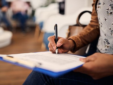Patient filling out dental insurance paperwork in lobby