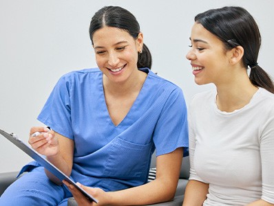 Dental assistant showing patient forms on clipboard