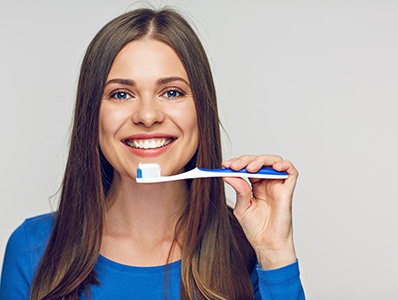 Woman in blue shirt holding a toothbrush