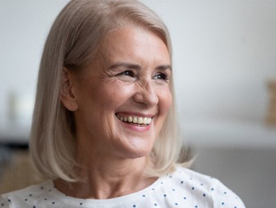 : woman smiling after getting dentures 