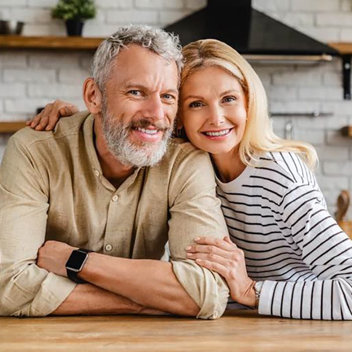 Older couple with dental implants in Annadale smiling at home