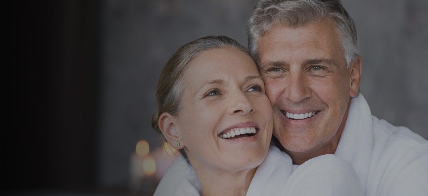 Older man and woman in white bathrobes smiling