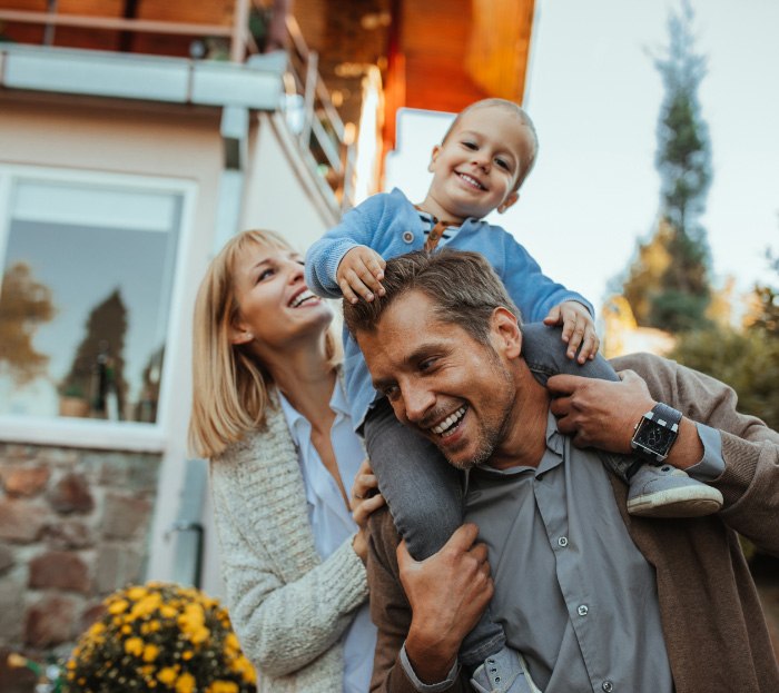 Family of three smiling together outdoors