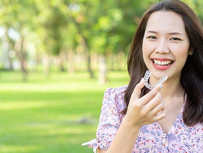 Smiling patient outside holding Invisalign in Annandale