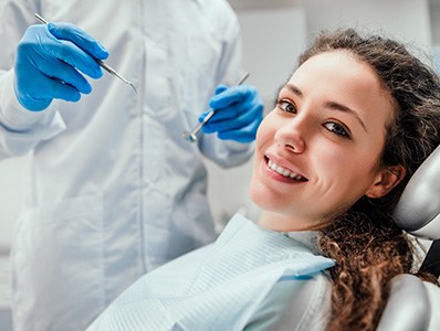 Woman smiling as dentist approaches for procedure