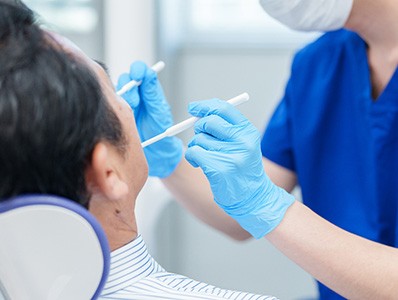 Dentist in blue scrubs and gloves performing procedure on patient