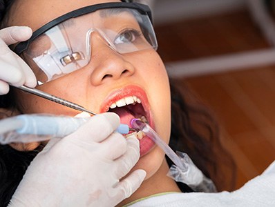 Woman in protective glasses undergoing dental treatment
