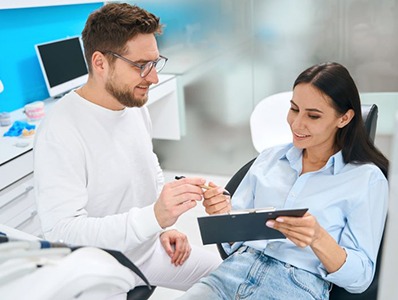 Dental patient in treatment chair, signing paperwork