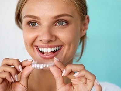 Smiling patient holding teeth whitening tray