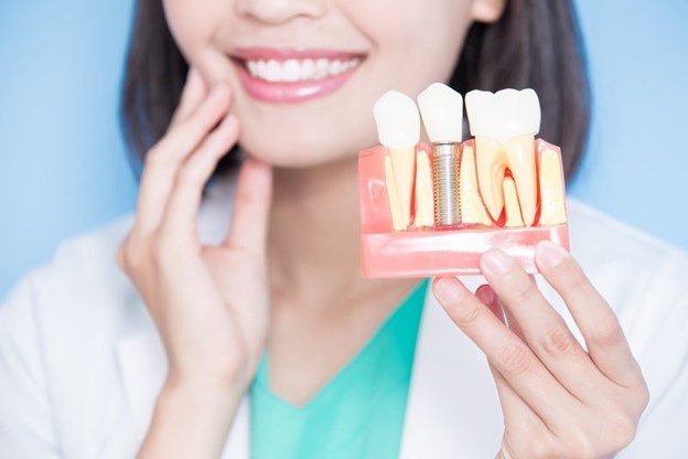 implant dentist holding an implant model