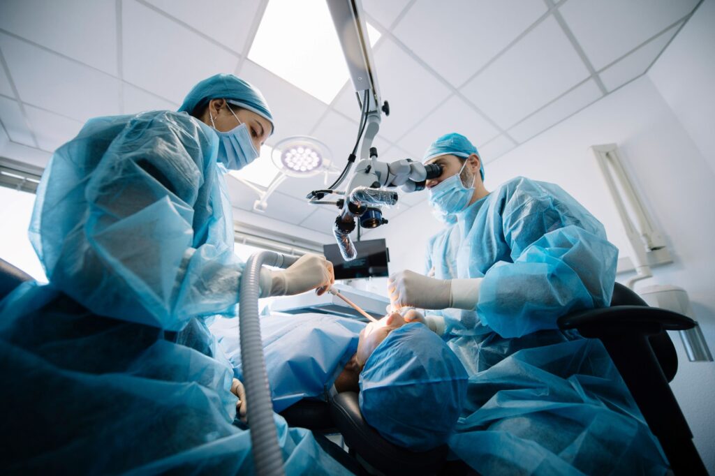 Dentists in blue scrubs performing oral surgery on patient