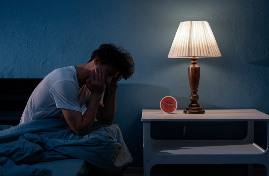 Man awake at night, clutching head